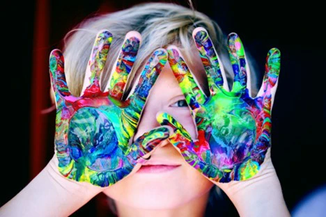 Child holding up multi-colored painted hands
